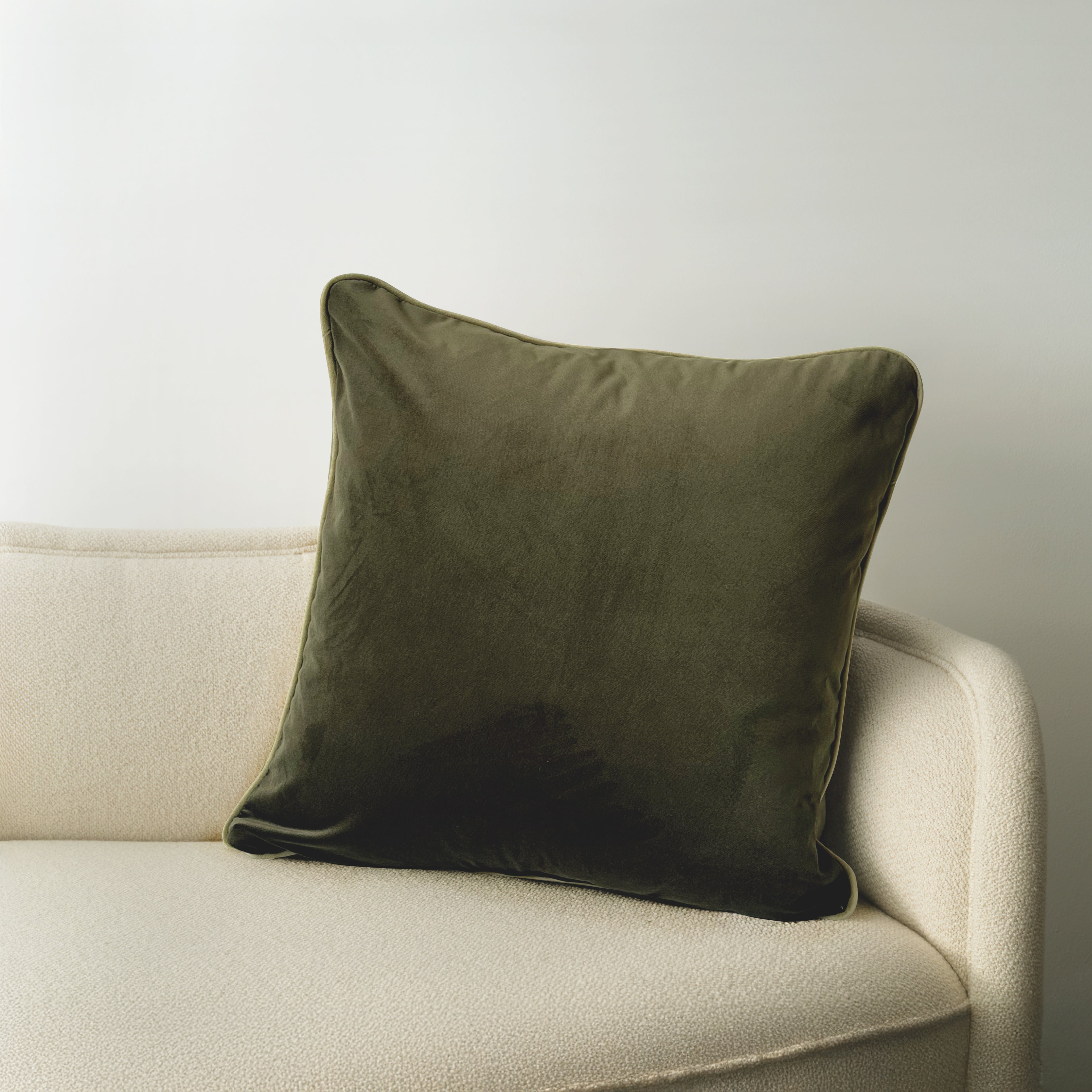 Square Atelier Cushion in Forest Noir velvet with contrasting piped edge resting on a neutral upholstered sofa